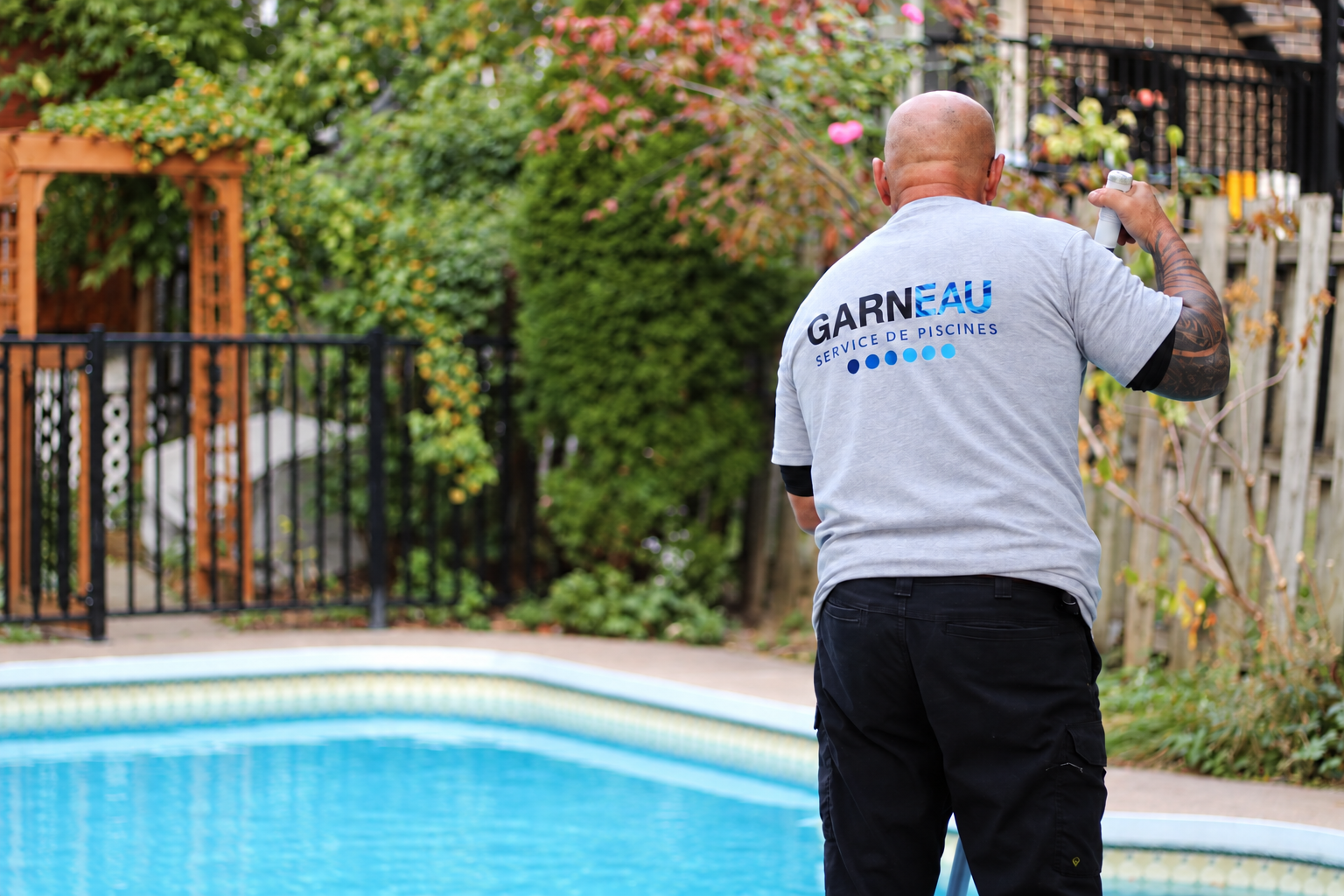 Serge nettoie une piscine, vêtu du chandail Garneau Service de Piscines
